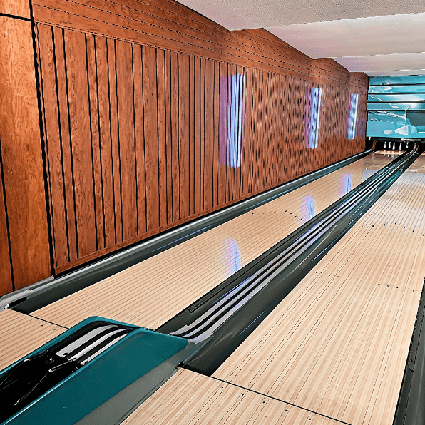 A modern bowling alley lane with wooden paneling and blue lights.